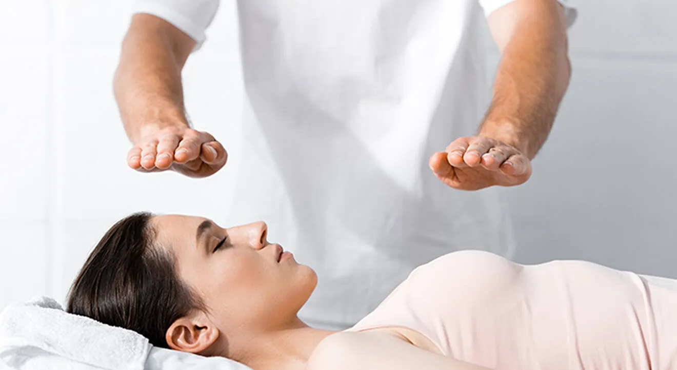 Praktisi mendampingi seseorang yang berbaring dalam sesi Reiki