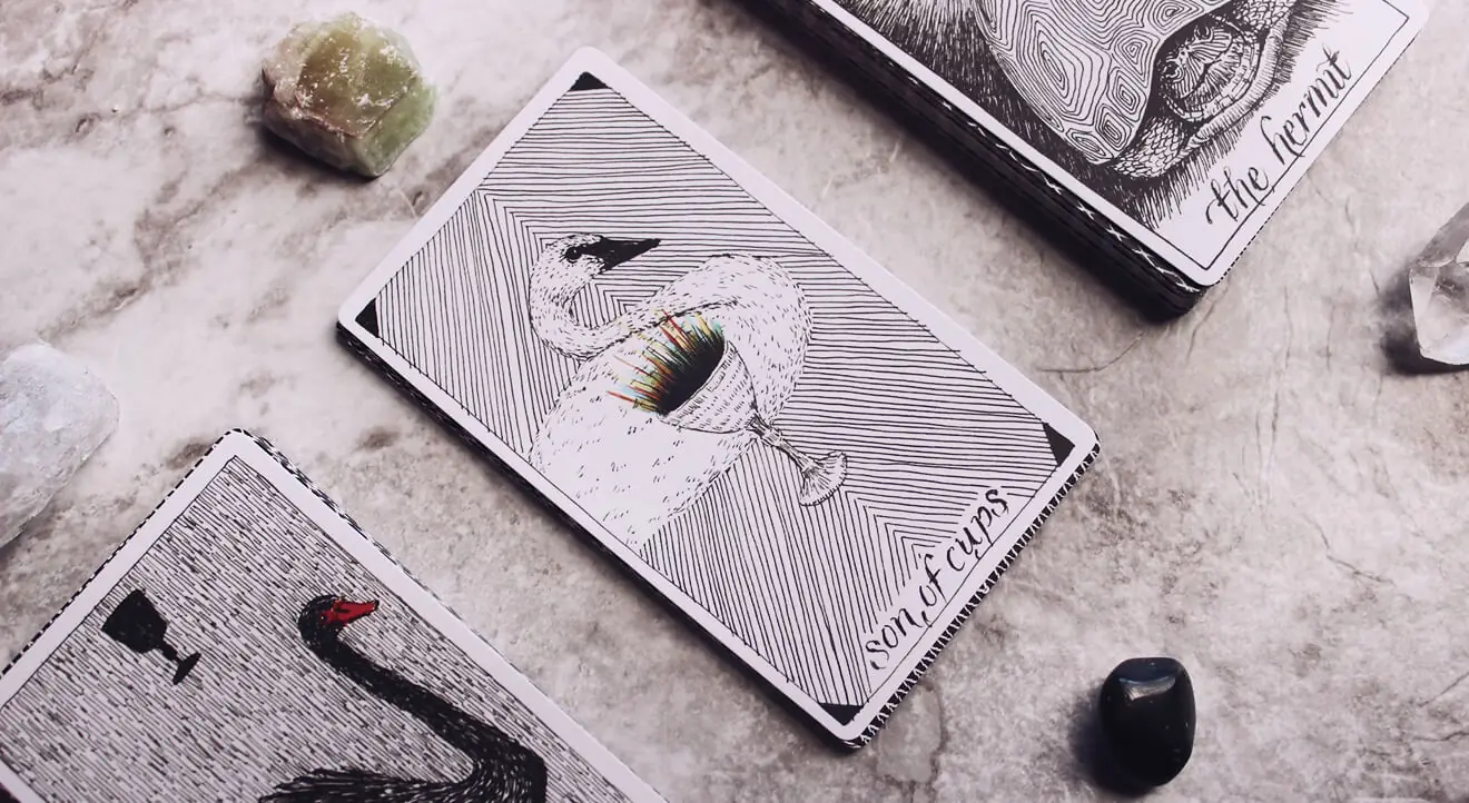 Kartu tarot dengan ilustrasi burung simbolis tersusun di dekat kristal
