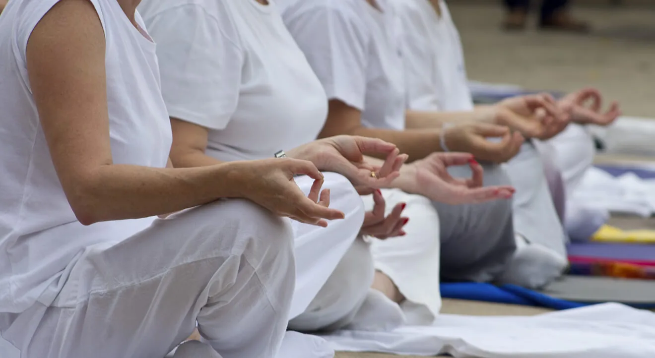 People seated together in meditation with hands resting on their knees